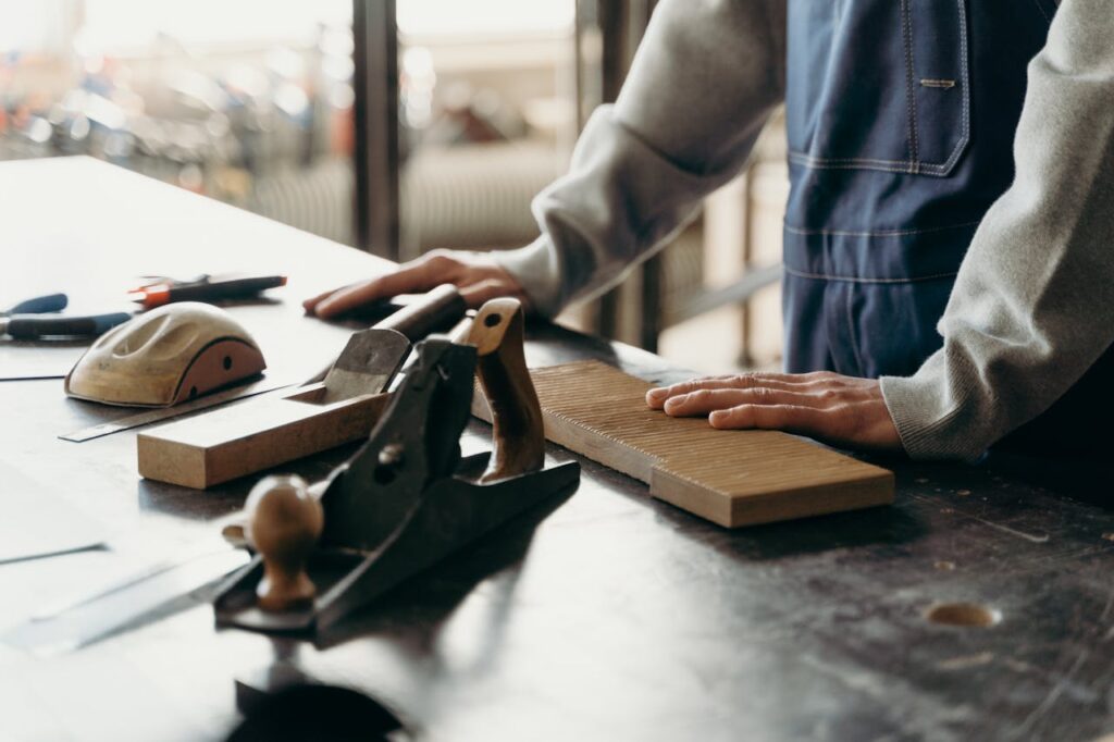 Person in Gray Long Sleeve Shirt Holding Brown Wooden Tool